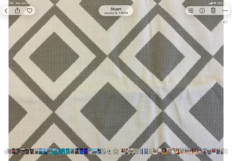 May include: A woven fabric featuring a repeating geometric pattern of large gray diamonds outlined by thick gray borders against a cream-colored background. The textile has a visible textured weave throughout, creating a consistent grid design.