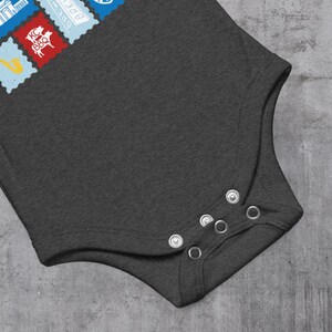 May include: Dark gray baby bodysuit with snap closures. The upper left corner features colorful postage stamp designs, including a red stamp with a pig and the text "KC BBQ".