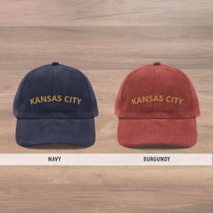 Puede incluir: Se muestran dos gorras de b&eacute;isbol de pana, una azul marino y otra burdeos. Cada gorra tiene bordado "KANSAS CITY" en hilo dorado. La gorra azul marino est&aacute; a la izquierda y la burdeos a la derecha. Estilo cl&aacute;sico.