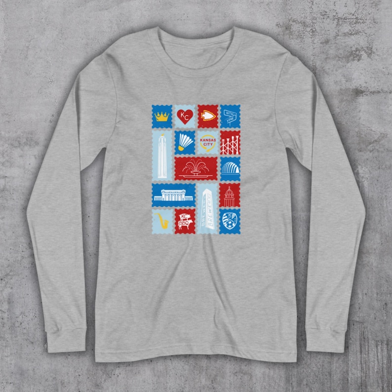 May include: A long-sleeved, heather gray shirt featuring a collection of colorful postage stamp designs. Each stamp showcases a different Kansas City landmark or symbol, including a crown, heart, and fountain. The stamps are arranged in a grid pattern.