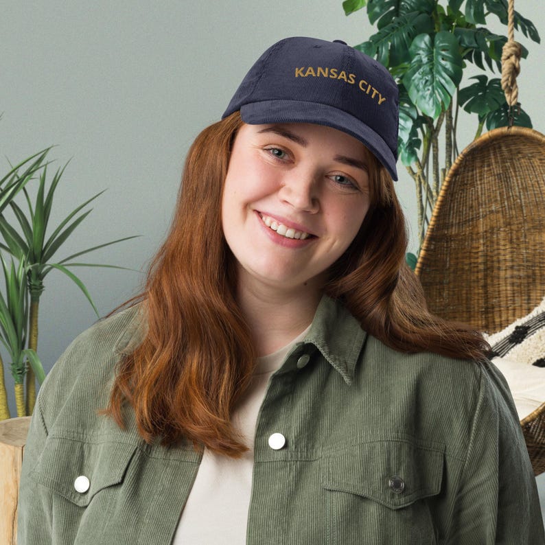 Puede incluir: Gorra de b&eacute;isbol de pana azul marino con la inscripci&oacute;n "KANSAS CITY" bordada en dorado. La gorra tiene una visera curva y un dise&ntilde;o cl&aacute;sico de seis paneles. Un accesorio elegante.
