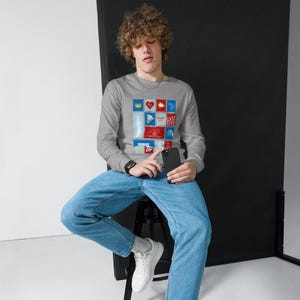 May include: A gray long-sleeve shirt featuring a colorful stamp design with various images and the text "KANSAS CITY". The shirt is made of a soft material and has a crew neck.