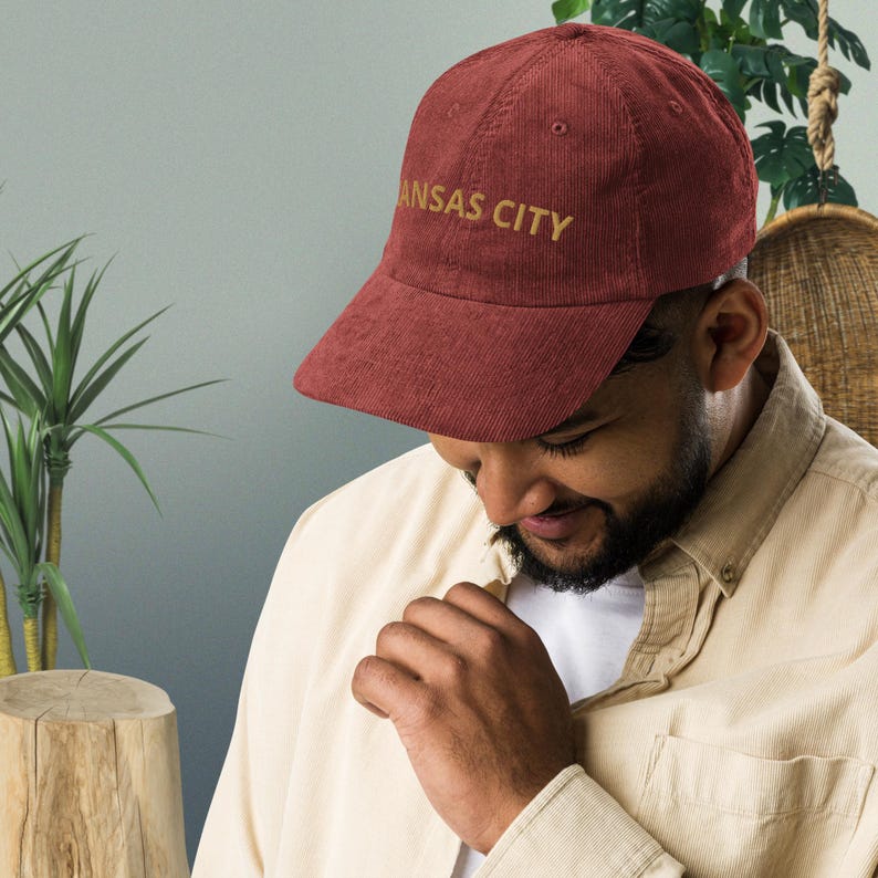 Puede incluir: Gorra de b&eacute;isbol de pana granate con el texto "KANSAS CITY" bordado en dorado. La gorra tiene una visera curva y una corona estructurada. Un accesorio de moda.