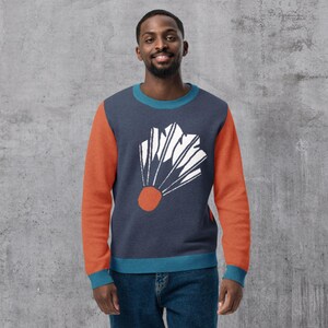 Op de afbeelding: Marineblauw sweatshirt met oranje mouwen en een teal halslijn en manchetten. De voorkant heeft een wit en oranje grafisch ontwerp. Het sweatshirt is gemaakt van een zacht, comfortabel materiaal.