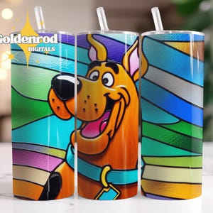 Pode incluir: Um conjunto de três canecas de aço inoxidável com um design colorido de vitral e uma imagem de desenho animado de Scooby-Doo. Cada caneca tem uma palhinha transparente e o texto "Goldenrod DIGITALS".