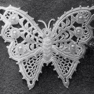 May include: A white, crocheted butterfly with intricate openwork patterns and pearl-like embellishments. The butterfly's wings feature delicate details and are symmetrical. The design is set against a dark background, highlighting the detailed craftsmanship.