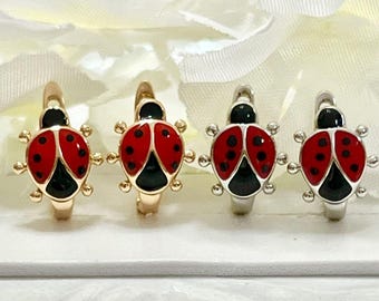 May include: Four hoop earrings shaped like ladybugs, featuring red and black enamel wings and bodies. Two earrings are finished in a gold tone, while the other two are finished in a silver tone, each with a hinged closure mechanism.