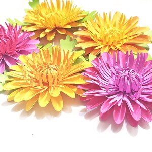 K&ouml;nnte beinhalten: F&uuml;nf Papierblumen, zwei gelbe und drei rosa, mit gr&uuml;nen Papierbl&auml;ttern. Die Blumen sind &uuml;bereinander gelegt und haben einen 3D-Effekt.