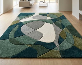 May include: A rectangular area rug featuring a multi-layered, abstract geometric pattern with curved, organic shapes. The design incorporates a palette of deep teal, forest green, olive, light gray, and cream, with carved textures creating depth.