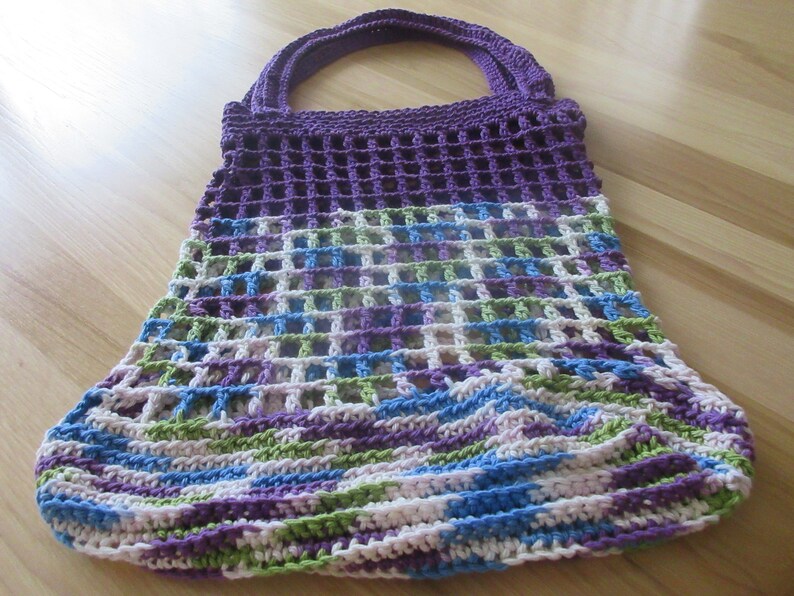 May include: A crocheted purple, green, blue, and white tote bag with a mesh design.