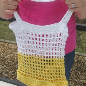 May include: A handmade crochet tote bag in white and yellow. The bag features a net-like design with a solid yellow bottom and white top. The bag has two white straps and a white handle.