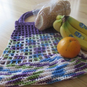 May include: A purple, green, blue, and white crocheted mesh bag with a loaf of bread and bananas inside. An orange is sitting on top of the bag.