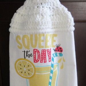 May include: White crocheted kitchen towel with a yellow button and a lemon-themed design. The towel has the text "Squeeze the Day" and a red ladybug on it.