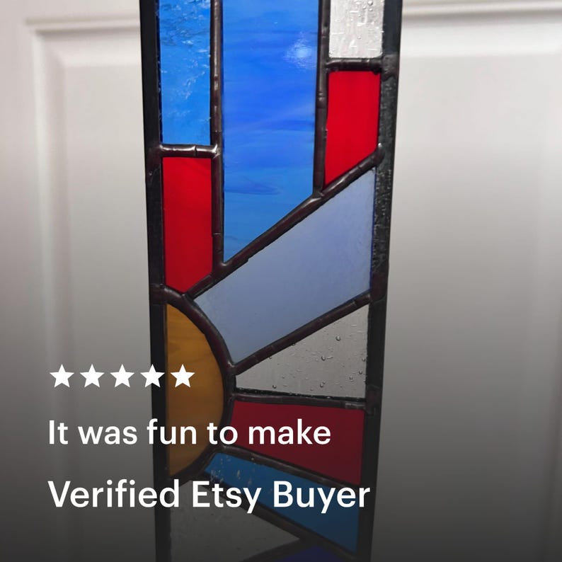 May include: A stained glass panel with a geometric design. The panel features sections of blue, red, yellow, and gray glass, framed by dark lines. The text "It was fun to make" and "Verified Etsy Buyer" are visible.