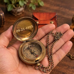 Peut inclure: Une boussole de poche en laiton avec un couvercle à charnière portant la date gravée 09-21-1995. La boussole présente un cadran circulaire avec des indications directionnelles et une fine chaîne métallique fixée sur le côté, au fini métallique.