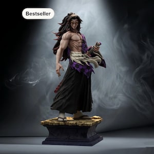 May include: A detailed figurine of a muscular character with long black hair and multiple eyes. The figure wears a black robe, purple and white accents, and holds a small weapon. The base is a stone-like structure. The word "Bestseller" is in a white oval.