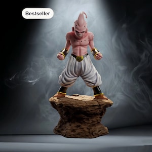 Könnte beinhalten: Eine rosa-weiße Figur eines Charakters aus Dragon Ball Z, die auf einem braunen Felsensockel steht. Die Figur hat einen muskulösen Körperbau, weiße Hose und goldfarbene Akzente. Das Wort "Bestseller" steht in einem weißen Oval oben links.