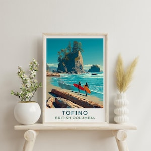 May include: A framed art print featuring a coastal scene with two figures carrying surfboards on a beach. The artwork depicts a vibrant turquoise ocean, sandy shore, and a large rock formation. The print includes the text "TOFINO BRITISH COLUMBIA".