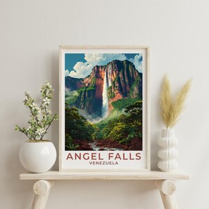 Può includere: Una stampa incorniciata delle Cascate dell'Angelo in Venezuela. L'opera raffigura una maestosa cascata che scende da una montagna, circondata da una vegetazione lussureggiante. Il testo "ANGEL FALLS VENEZUELA" è stampato in grassetto, in rosso, in basso.