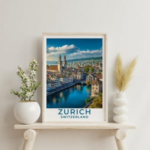 May include: A framed print of Zurich, Switzerland, showcasing a scenic view of the city with a river, buildings, and mountains under a blue sky. The print includes the text "ZURICH SWITZERLAND" in a navy blue font.