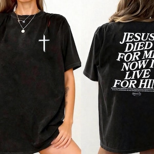 May include: Black t-shirt featuring a white cross on the front and the text "JESUS DIED FOR ME NOW I LIVE FOR HIM" on the back. The shirt has a faded, vintage appearance.