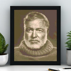 May include: Framed portrait of a man with a white beard and a knitted sweater. The portrait is in a black frame and is displayed on a white surface. The image has a sepia tone.