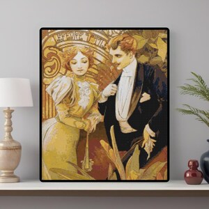 May include: A framed art print depicting a couple in period clothing. The woman is in a yellow dress, and the man wears a black tuxedo. The background has an Art Nouveau design with gold and brown hues. The print is on a white shelf.