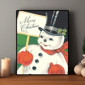 May include: A framed vintage Christmas print featuring a smiling snowman wearing a black top hat, red scarf, and orange mittens. The snowman holds a sign that reads "Merry Christmas" against a green background.