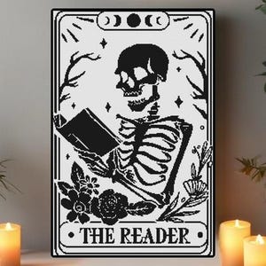 Pode incluir: Impressão artística emoldurada em preto e branco com um esqueleto lendo um livro. A imagem é um design de carta de tarô com as palavras "THE READER" na parte inferior. A obra de arte inclui elementos florais e celestiais.