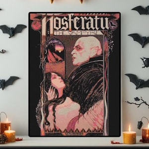 May include: A framed poster featuring the movie title "Nosferatu the Vampyre" with a vintage design. The artwork depicts a bald man and a woman in a gothic style, with a black background and red and pink accents. Halloween decor.