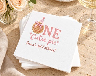 May include: A stack of white square paper napkins featuring a pink graphic of a pie wearing a party hat, the text ONE Cutie pie, and the personalized text Emma's 1st birthday in a pink script font, accented with small pink hearts.