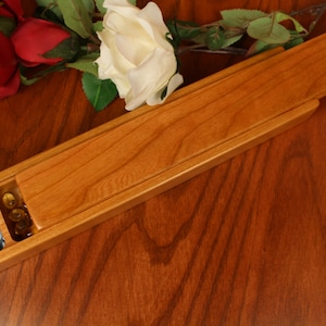 May include: A wooden pill box with a sliding lid, divided into two compartments. One compartment contains blue pills and the other contains yellow pills.