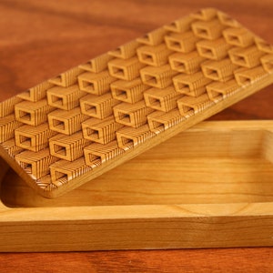 May include: A wooden box with a geometric pattern lid. The box is made of light wood and has a natural finish. The lid is open and the inside of the box is visible.