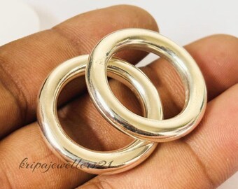 Könnte beinhalten: Zwei silberfarbene, kreisförmige Ringe. Die Ringe haben eine glatte, glänzende Oberfläche und eine abgerundete Form. Sie werden auf einer hautfarbenen Oberfläche präsentiert. Der Text "kripajeweller21" ist sichtbar.