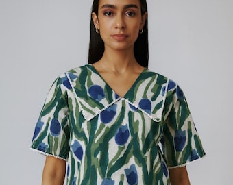Puede incluir: Conjunto de dos piezas a juego con top de manga corta y shorts. El conjunto presenta un estampado floral verde y azul sobre un fondo blanco. El top tiene cuello y ribete blancos. Los shorts tienen un ribete blanco a juego.