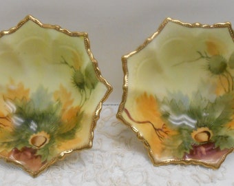 May include: Two antique porcelain bowls with gold trim and a floral design. The bowls are shaped like a star and have a scalloped edge.