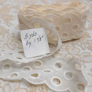 May include: White eyelet lace trim with a scalloped edge. The trim is 1 7/8 inches wide and comes in a 5 yard roll.