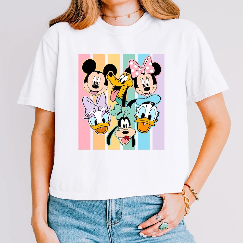A woman wearing a white t-shirt with a colorful graphic of Disney characters on it.