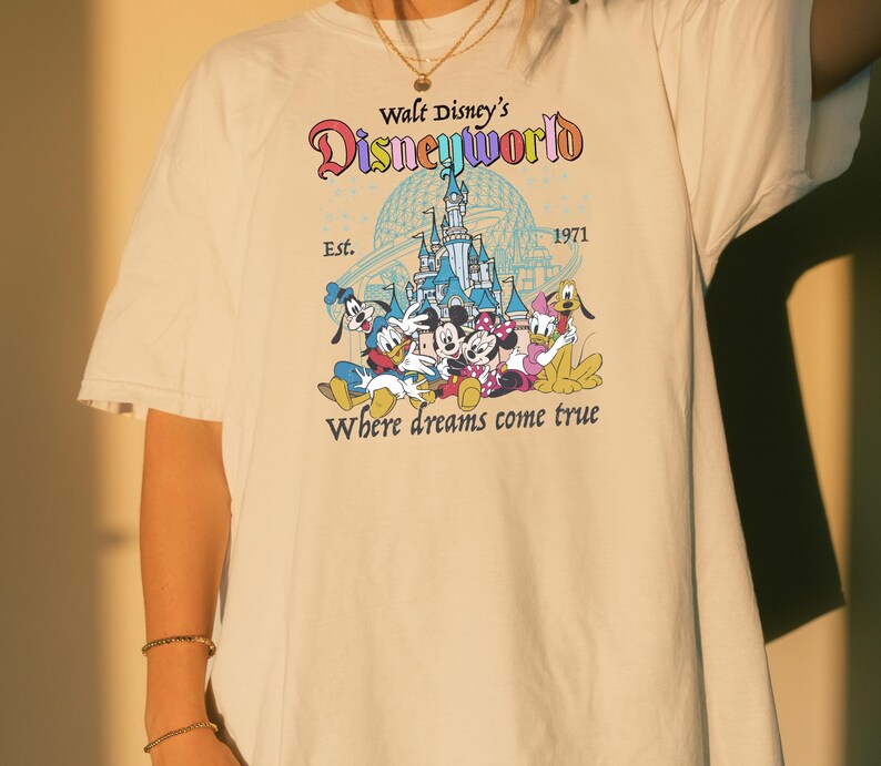 A person wearing a white t-shirt with a Disney World logo and text printed on it.