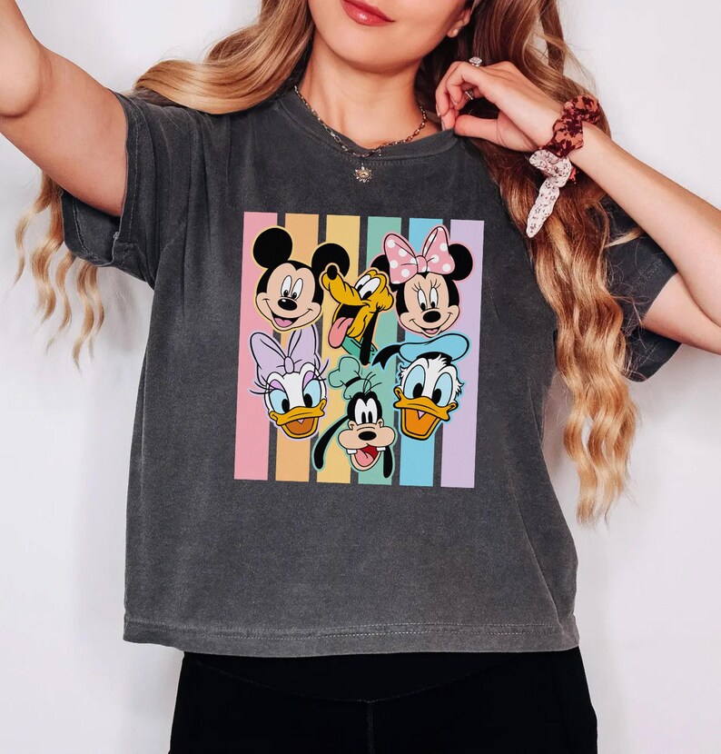 A woman wearing a gray t-shirt with a graphic of Disney characters Mickey Mouse, Minnie Mouse, Goofy, Donald Duck, and Pluto.