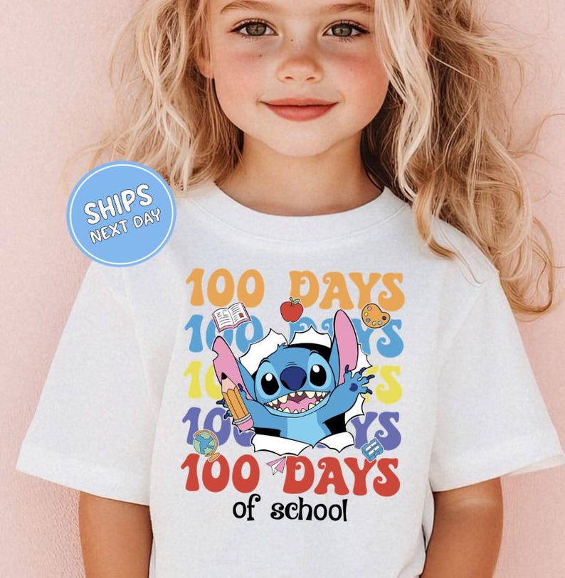 A young girl wearing a white t-shirt with a graphic design featuring a cartoon character and the text "100 DAYS of school".