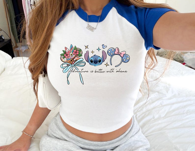 A person wearing a white and blue crop top with a graphic design featuring characters from the Disney movie Lilo and Stitch.
