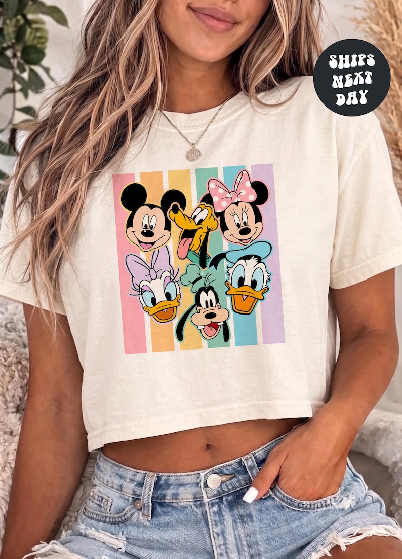 A woman wearing a white crop top with a graphic of Disney characters on it.