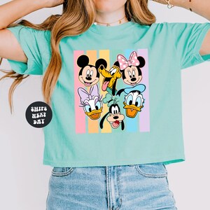 A woman wearing a turquoise crop top with a graphic of Disney characters on it.