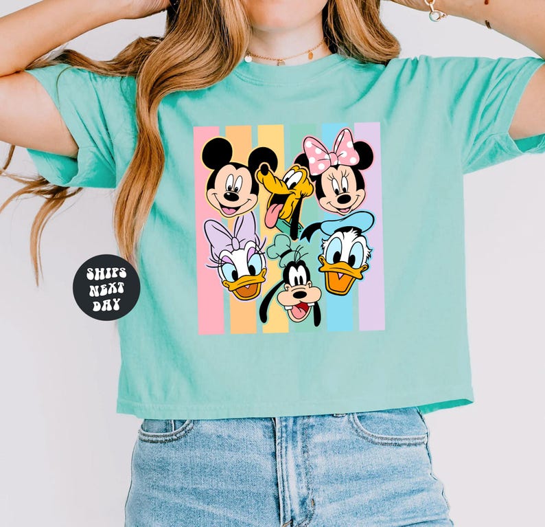 A woman wearing a turquoise crop top with a graphic of Disney characters on it.