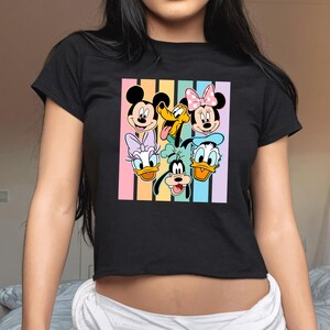 A woman wearing a black t-shirt with a colorful graphic of Disney characters on it.