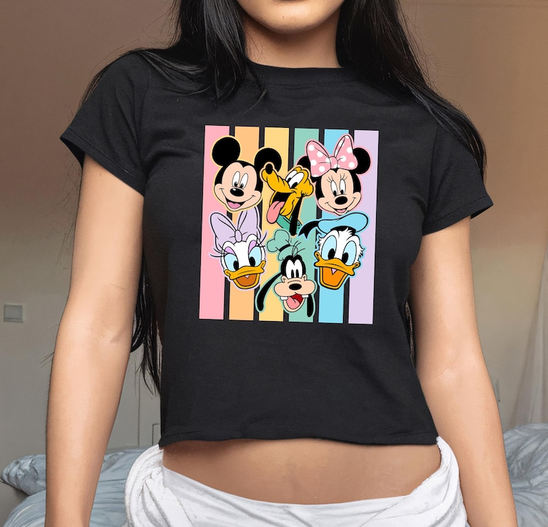 A woman wearing a black t-shirt with a colorful graphic of Disney characters on it.