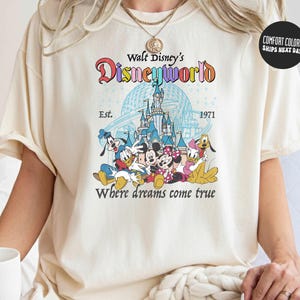 A person wearing a white t-shirt with a Disney World logo and text printed on it.