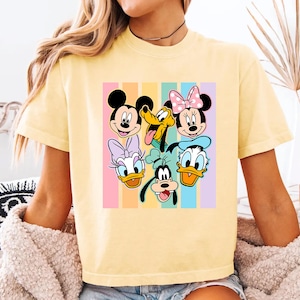 A yellow t-shirt with a colorful graphic of Disney characters such as Minnie Mouse, Mickey Mouse, Donald Duck, Goofy, and Pluto.