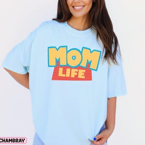 a woman wearing a blue shirt with the word mom life on it